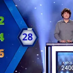 Karol Fedoruk w studiu telewizyjnym, obok planszy z liczbami i wynikiem 2400.