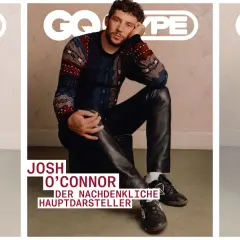 Josh O'Connor, der nachdenkliche Hauptdarsteller, sitzt lässig in Lederhosen und einem gemusterten Pullover.