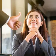 Frau freut sich über Lob, Daumen hoch als positives Feedback. Tolle lob beispiele für Mitarbeiter.