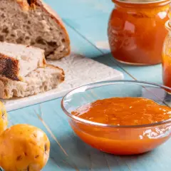 Pane rustico, nespole fresche e una ciotola colma di deliziosa marmellata di nespole, pronta per essere gustata.