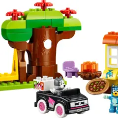 Bluey und Bingo spielen mit LEGO DUPLO im Wald. Ein Baumhaus, ein Auto und eine kleine Hütte sind aufgebaut.