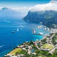 Widok na zatokę z łodziami i miasteczkiem na zboczu góry Capri.