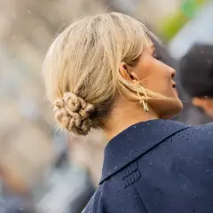 Chignon facile e intrecciato, con orecchini dorati a forma di croce.
