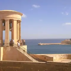 Malta, kwiecień: słoneczna pogoda nad portem, widok na zabytkową wieżę z dzwonami i fortyfikacje.