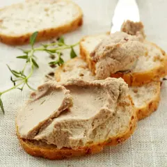 Chrupiące kromki bagietki z pyszną, kremową włoską pastą z wątróbki, ozdobione gałązką świeżego tymianku.