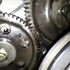 Zbliżenie na mechanizm zębatek, kluczowe dla ustawienia pompy wtryskowej Perkins 4. Widoczne śruby i smar.