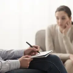 Psychoterapeuta notuje podczas sesji. Zastanawiasz się, ile zarabia psychoterapeuta? To zależy od wielu czynników.