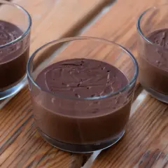 Tre glas med krämig, hemmagjord chokladpudding står på en träyta.