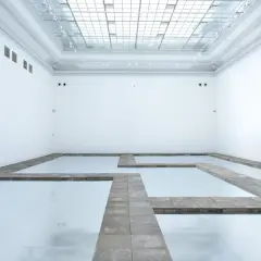 Biała przestrzeń galerii z lustrzaną podłogą i kamiennymi ścieżkami tworzącymi labirynt. Kojący widok, jakbyś spacerował po chmurach.