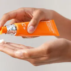 Mani che dosano una crema con vitamina C sulla pelle, per un trattamento illuminante e antiossidante.