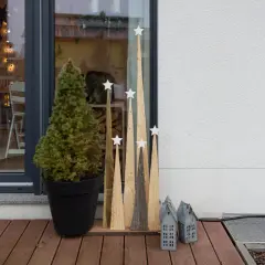 Selbstgemachte Weihnachtsdeko außen: Tannenbaum im Topf, Holz-Tannenbäume mit Sternen und kleine Lichterhäuser auf einer Holzterrasse.