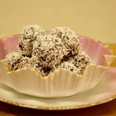 En skål med chokladbollar, perfekta för ett enkelt delicatobollar recept. Kokosflingor täcker de mörka bollarna.