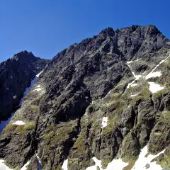 Skaliste zbocza górskie z resztkami śniegu, ukazujące majestat najwyższego szczytu Karpat.