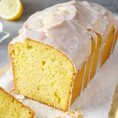 Saftiger Zitronenkuchen mit Zuckerguss, perfekt für Ihr nächstes zitronenkuchen rezept. Ein Stück ist bereits angeschnitten.