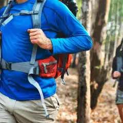 Un hombre y una mujer caminan por un sendero boscoso, ambos con una mochila mountain lista para la aventura.