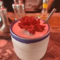 Un cocktail crémeux orné d'une fleur rouge, prêt à être dégusté. Un vrai "menu de bar-bisou" pour une soirée douce.