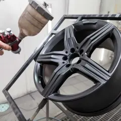 Un professionista mostra come verniciare i cerchi in lega con uno spray gun, dando un nuovo look all'auto.
