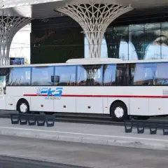Biały autobus PKS Biłgoraj na nowoczesnym dworcu autobusowym z zieloną ścianą i futurystycznym zadaszeniem.