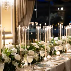 Elegancka dekoracja stołu weselnego z białymi kwiatami i świecami. Sprawdź, jaka jest florystka na wesele cena za takie cuda.