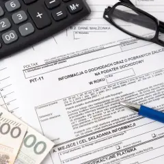 Dokument PIT-11, kalkulator, okulary i polskie banknoty. Przygotowanie do rozliczenia podatku dochodowego.