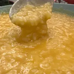 Un mestolo solleva una porzione cremosa di riso e patate, un piatto confortante e dorato.