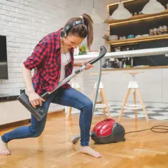 Frau mit Kopfhörern spielt Staubsauger-Gitarre. So macht **family fitness** Spaß!
