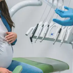Ciężarna kobieta w gabinecie stomatologicznym, omawiająca leczenie kanałowe.