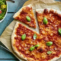 En saftig pizza med tomatsås och ost, toppad med färsk basilika. Bredvid en fräsch sallad med gröna bönor och tomater. En nyttig pizza för hela familjen.