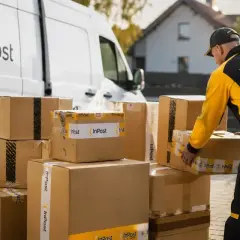 Kurier InPost odbiera paczki. Kiedy będzie moja przesyłka? Stos paczek czeka na odbiór przez kuriera InPost.