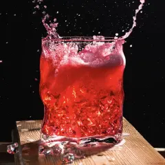 Intensywny drink z wiśniówką w szkle, z rozpryskującym się płynem i lodem.