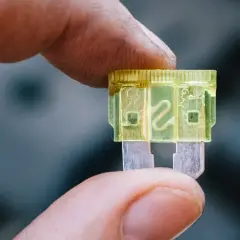 Dedo sostiene un fusible luz de freno amarillo de 20 amperios, listo para reemplazar uno quemado.