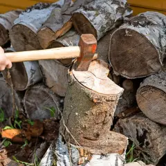 Holz spalten mit Axt. Auch wenn es nass wird, darf Brennholz so gelagert werden, bis es trocken ist.