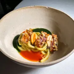 Un piatto di pasta con frutti di mare, salsa verde e rossa, croccantezza e un tocco da ciccio sultano stelle michelin.