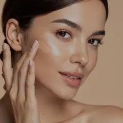Donna applica fondotinta sul viso, un passo essenziale per capire come scegliere fondotinta perfetto per la tua pelle.