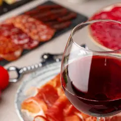 Glas Rotwein neben Aufschnitt und Tomaten. Ein Fest für Genießer, das den Unterschied Portwein Sherry erahnen lässt.