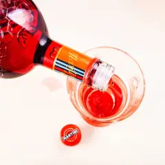 Czerwony Martini Fiero Prosecco nalewany do kieliszka. Obok leży zakrętka.