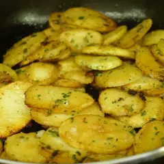 Patatas panaderas al horno crujientes, doradas y con perejil picado, listas para disfrutar.