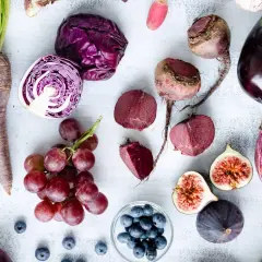 Un surtido de verduras raras y frutas moradas: zanahorias, col lombarda, remolachas, berenjenas, higos, uvas y arándanos.