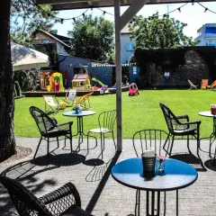 Relaks przy stoliku w restauracji z placem zabaw w Warszawie. Dzieci bawią się na zjeżdżalni, a dorośli odpoczywają na tarasie.
