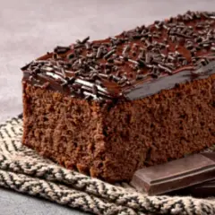 Un delicioso pastel de chocolate cubierto con glaseado y chispas de chocolate, acompañado de trozos de chocolate.
