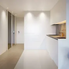 Pasillo moderno con arte abstracto y cocina minimalista, creando un ambiente de flujo luminoso.