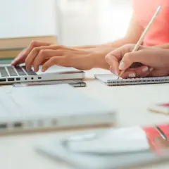 Dwie osoby uczą się, jedna pisze na laptopie, druga notuje. Odkryj skuteczne sposoby na szybką naukę.