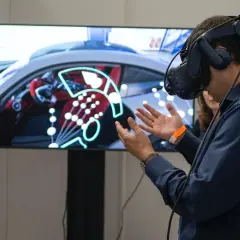 Un homme porte un casque de réalité augmentée, explorant un tableau de bord de voiture virtuel.
