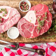 Deux belles pièces de viande blanche, du sel, des poivres, du thym et un piment rouge sur une planche en bois.