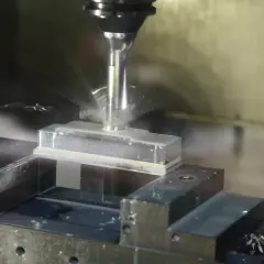 Precyzyjne frezowanie aluminium na maszynie CNC. Chłodziwo rozpryskuje się wokół obrabianego elementu.