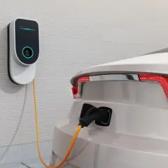 Nowoczesna stacja ładowania samochodów elektrycznych podłączona do białego auta. Sprawdź, jaka jest stacja ładowania samochodów elektrycznych cena.