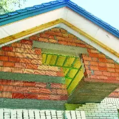 Budowa ściany szczytowej z cegły, widoczna izolacja i elementy konstrukcji dachu.