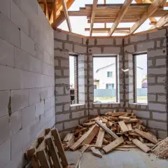 Interno di una casa in costruzione con muri in blocchi di cemento, tetto in legno e cumuli di legname. Forse un caso di abuso edilizio prescrizione.