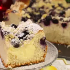 Szybkie ciasto z budyniem i jagodami, posypane cukrem pudrem i kruszonką. Idealne na deser.