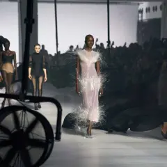 Mannequins défilent sur un podium, une robe ornée de plumes, un aperçu de la Paris Fashion Week 2026.
